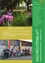 Ein Poster zeigt einen farbenfrohen Garten mit violetten Blumen. Darunter steht der Text 'Spatenstich Feuerwehrhaus' mit einer Beschreibung des neuen Feuerwehrhauses. Unten auf dem Bild sind Menschen in Uniformen mit Fahnen abgebildet, und es gibt weiteren Text in Deutsch.