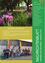 Ein Poster zeigt einen farbenfrohen Garten mit violetten Blumen. Darunter steht der Text 'Spatenstich Feuerwehrhaus' mit einer Beschreibung des neuen Feuerwehrhauses. Unten auf dem Bild sind Menschen in Uniformen mit Fahnen abgebildet, und es gibt weiteren Text in Deutsch.
