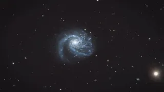 A spiral galaxy with a bright core and multiple arms, surrounded by numerous stars against a dark sky.