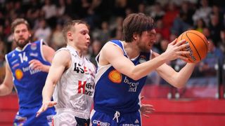Two basketball players, one in white and the other in blue, are competing on a court. The player in white wears jersey number 45, while the player in blue has a jersey with a logo and the word 'buren'. They are both intense and focused on the game.