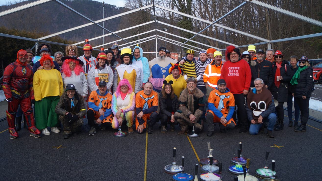 A group of people dressed in various costumes are posing for a photo under a tent with trees in the background.