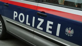 A close-up view of a police car with blue, white, and red stripes. The word 'POLIZEI' is written in white font on the blue stripe.