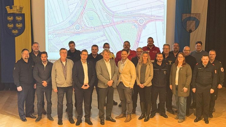 Eine Gruppe von Menschen steht vor einer großen Leinwand mit einer Karte. Sie sind geschäftlich gekleidet, und der Ort scheint ein Büro zu sein.