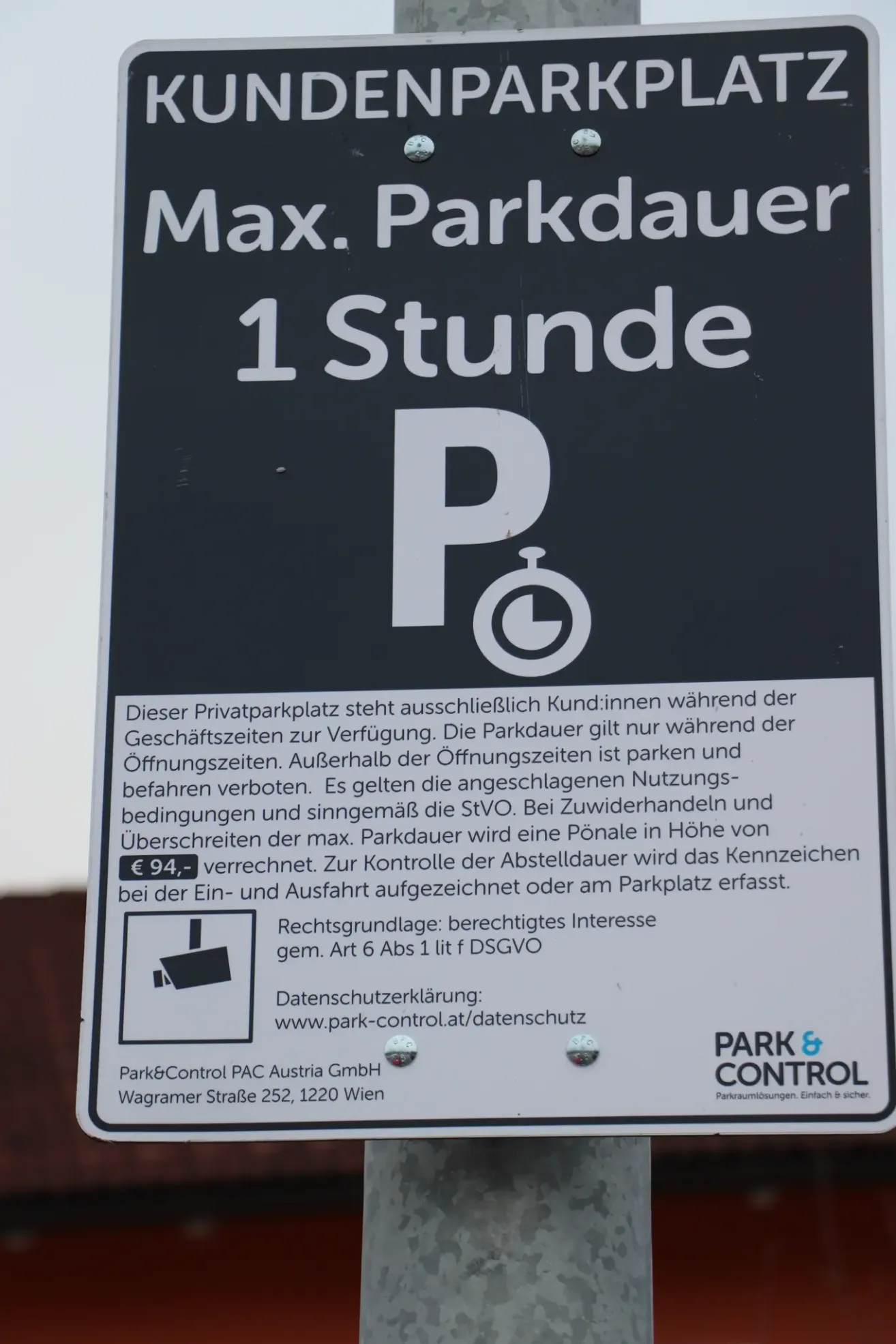 Ein privater Parkschein zeigt an, dass ein maximaler Aufenthalt von einer Stunde während der Geschäftszeiten erlaubt ist. Das Parken ist gestattet und kostenlos. Das Überschreiten ist verboten. Zuwiderhandelnde können mit einer Geldstrafe von bis zu 94 Euro belegt werden. Der Schild enthält ein Logo und Details zur Datenschutzerklärung.