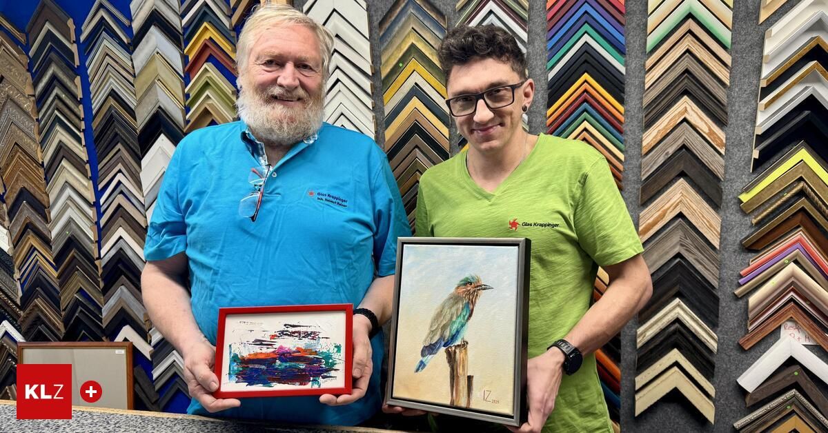 Zwei Männer posieren mit gerahmten Kunstwerken. Der Mann auf der linken Seite hält ein farbenfrohes abstraktes Gemälde, während der Mann auf der rechten Seite ein gerahmtes Gemälde eines Vogels auf einem Ast hält.