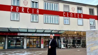 Ein Mann steht vor dem Gicia Center, einem Geschäftsgebäude mit vielen Fenstern, vor einem Café.