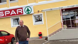 Ein Mann steht vor einem gelben Gebäude mit einem Schild, das GAR sagt. In der Nähe befindet sich ein Mülleimer.