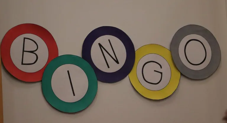Four circular stickers are arranged in a row. The first is green with an 'I', the second is blue with an 'N', the third is yellow with a 'G', and the fourth is red with no letter.