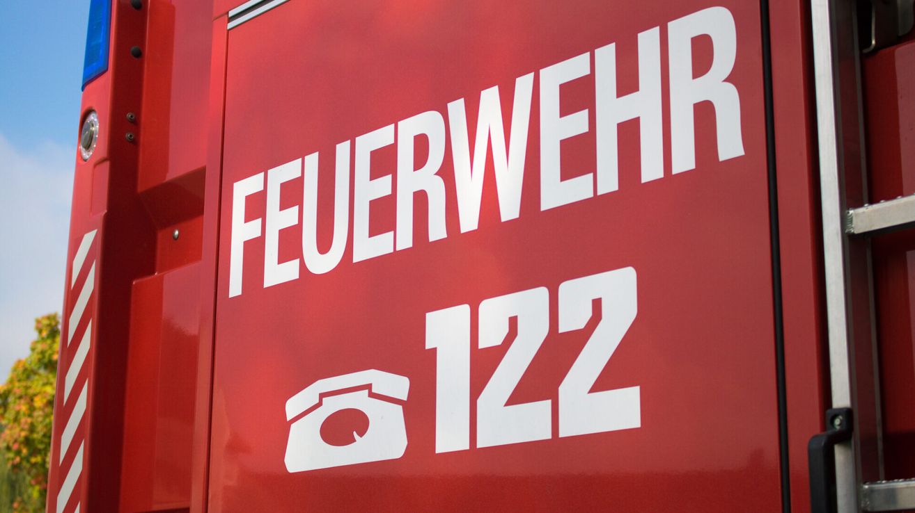 A red sign displays the text 'FEUERWEHR' and the number '122' with a phone icon. The sign is likely related to a fire department.
