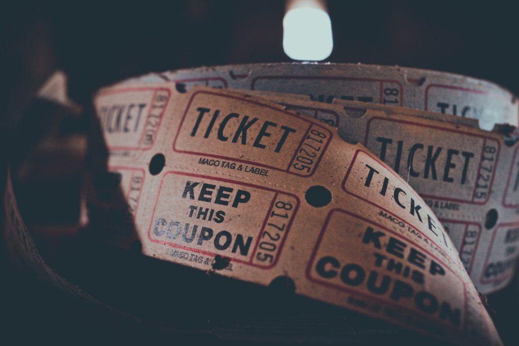 A close-up of old, worn tickets and coupons, some labeled 'TICKET' and 'KEEP THIS COUPON.' They have a vintage look, with a light shining on them.