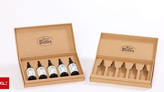 Two brown cardboard boxes filled with six bottles of Bauers Bitter, labeled with their names and ingredients. The boxes are open, displaying the bottles inside.