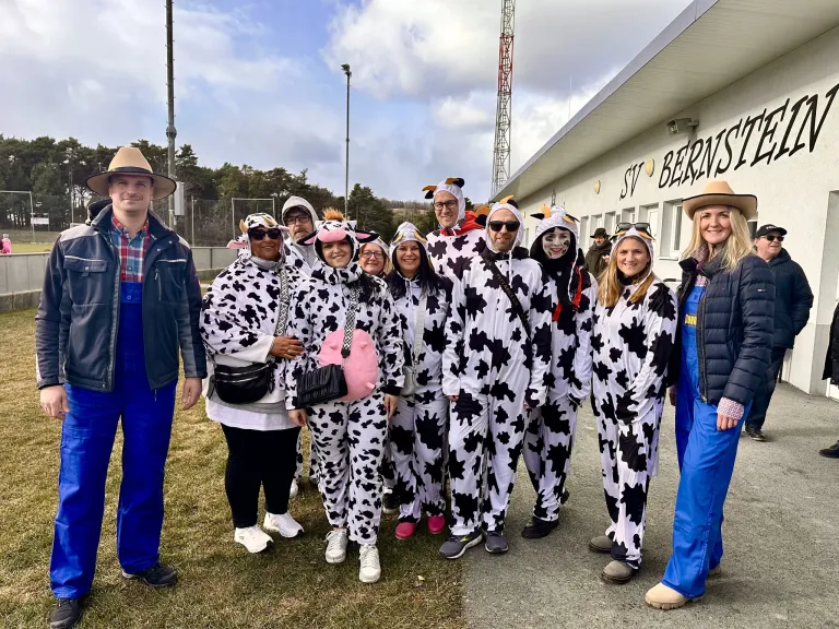Eine Gruppe von Menschen in Kuhkostümen posiert für ein Foto vor einem Gebäude mit dem Schild ST V BERNS.