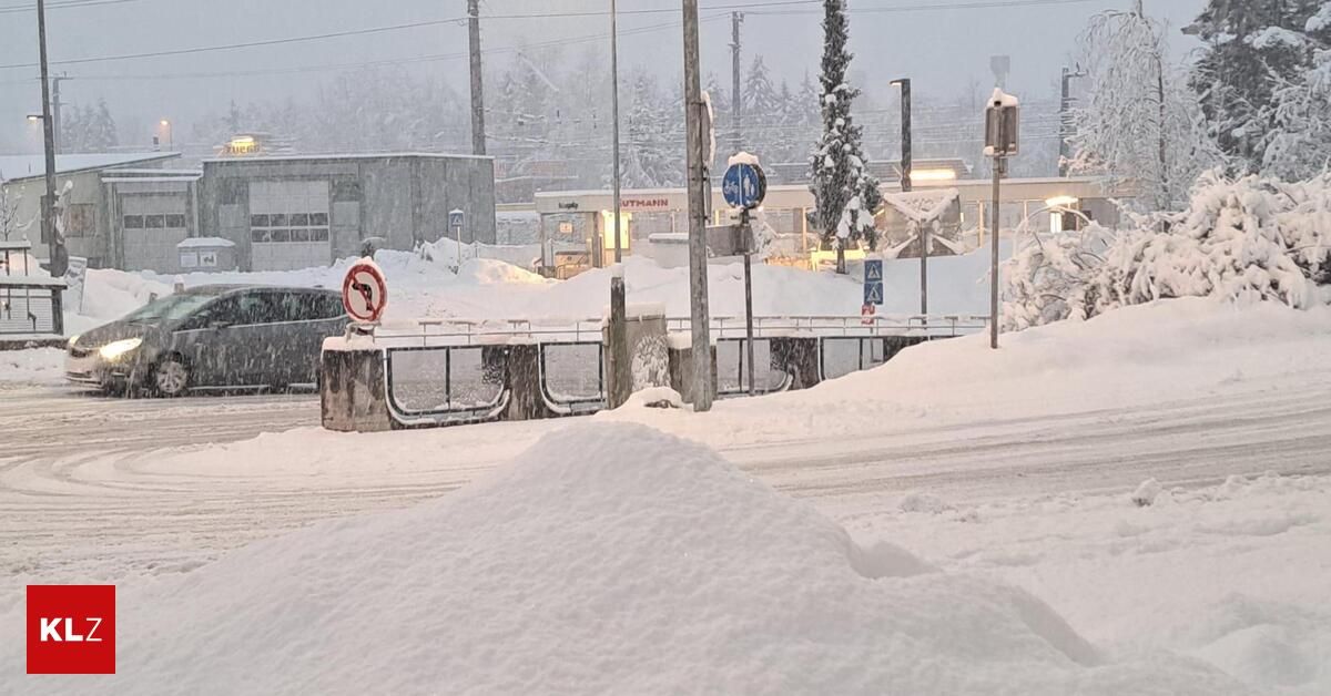 Snow-covered street with barriers and signs, near a building with a sign that reads UTMANN.