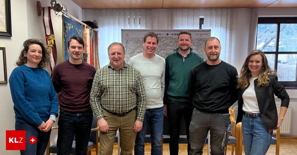 Fünf Männer stehen eng beieinander vor einer Karte und lächeln für ein Foto. Dahinter ist eine große Karte an der Wand befestigt.