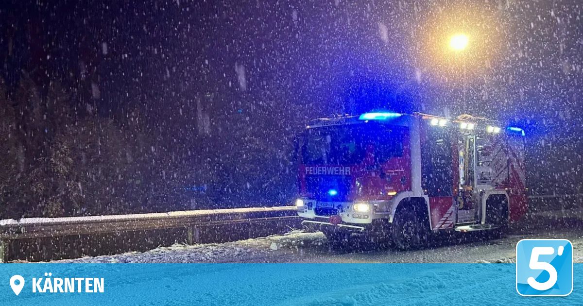 A fire truck is driving on a snowy road at night with its headlights and emergency lights on.