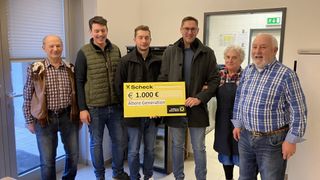 Five men and a woman pose for a photo holding a check for 1,000 euros from Raiffeisen Meine Bank.