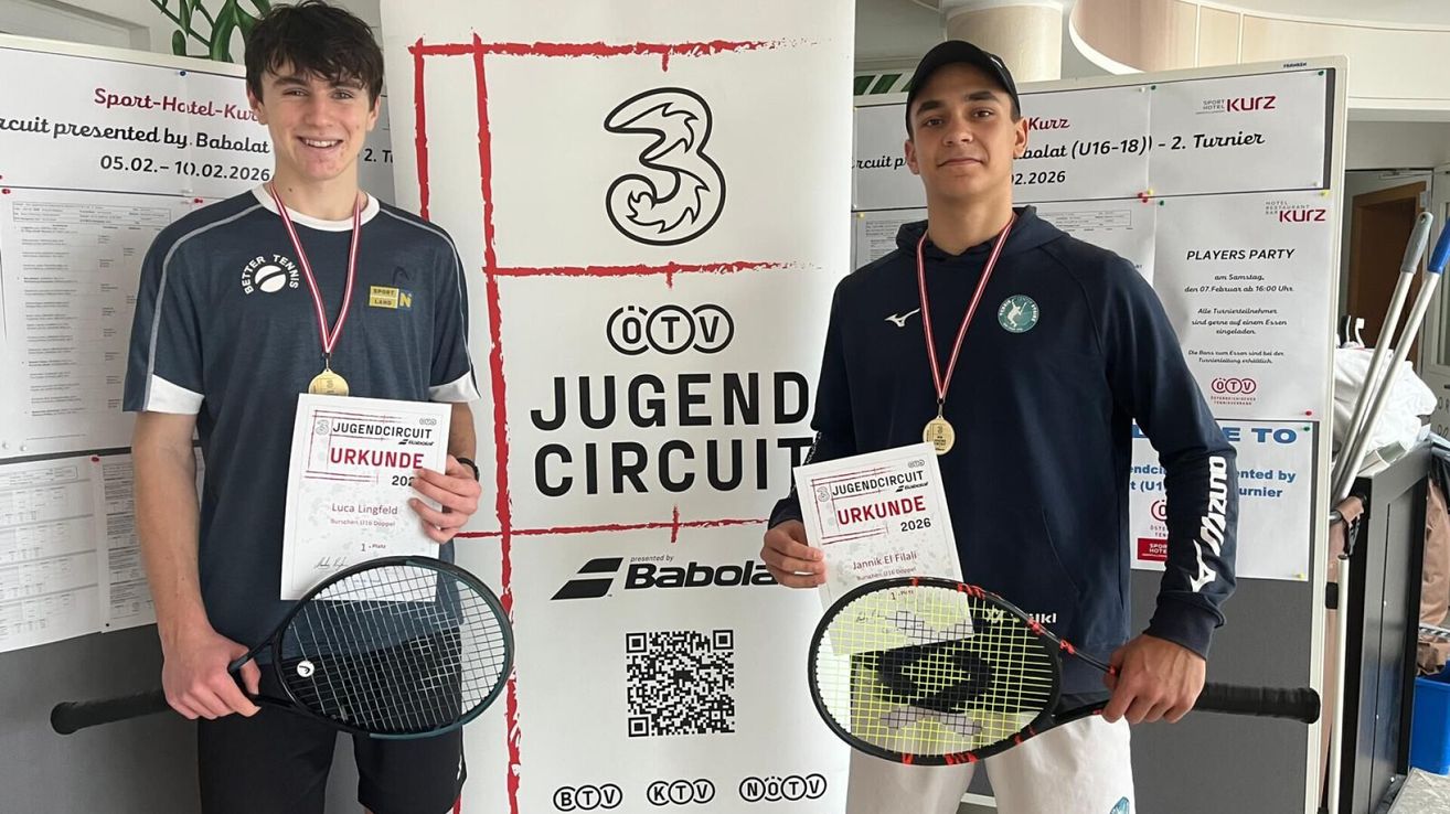 Two men pose with rackets and medals in front of a sign reading 'Jugend Circuit Urkunde 2026'. They hold certificates, one labeled 'Luca Lingfeld' and the other 'Jannik El Fialli'. Both wear caps and jackets with logos. Behind them, a QR code is displayed on a white banner.