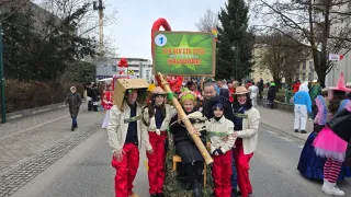 Group photo of people in red pants and white jackets. They are posing in a street with a sign saying 'Ich bin ein Star'. Behind them, there are buildings, trees, and people walking.