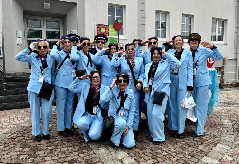 Eine Gruppe von Menschen in blauen Uniformen posiert für ein Foto vor einem Gebäude mit einem Erdbeerschild.