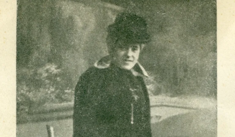Ein altes Foto einer Person, die Hut und Jacke trägt. Die Person hat einen ernsten Ausdruck.