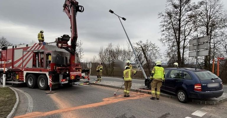 Feuerwehrleute räumen die Straße nach einem Autounfall auf. Das Fahrzeug steht am Straßenrand, und ein Kran ist in der Nähe.