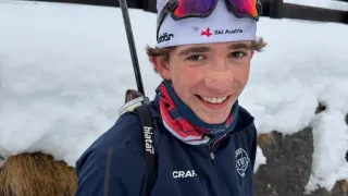 Eine Person steht im Schnee und trägt eine Skijacke, eine Skibrille und eine Ski Austria-Mütze und lächelt in die Kamera.