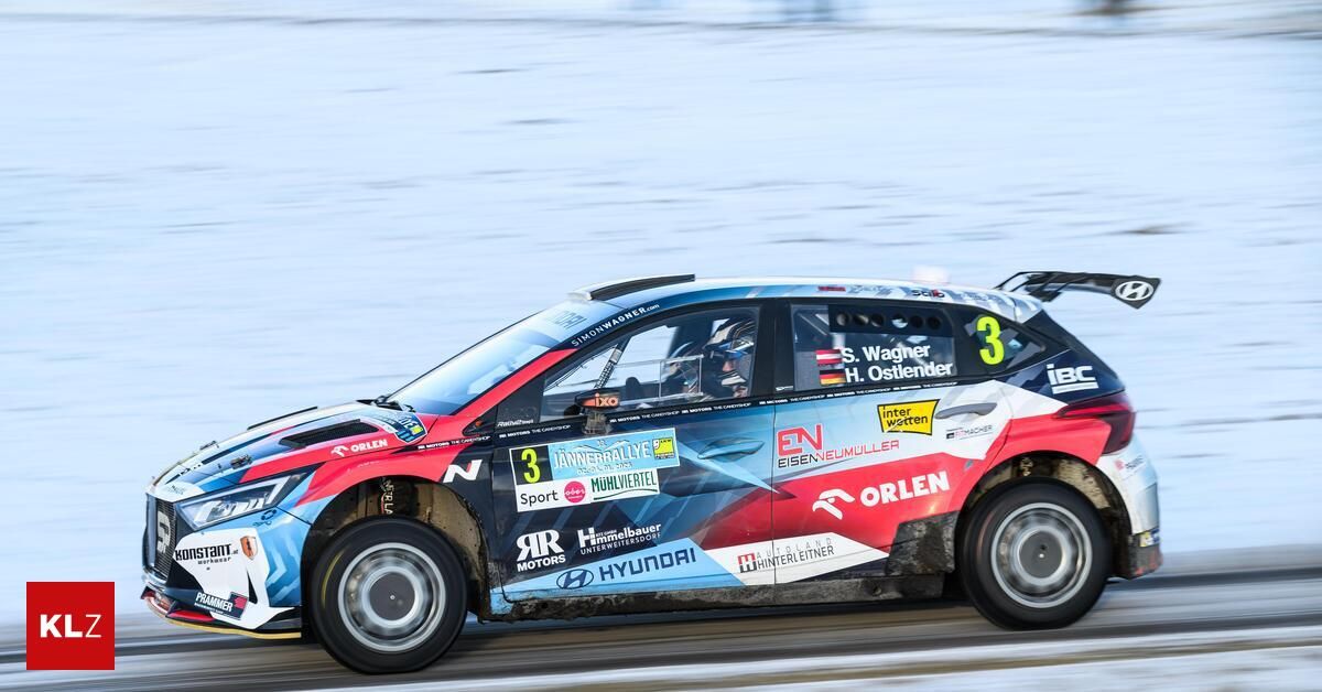 Ein Rallyeauto mit der Nummer 3 auf der Seite fährt auf einer verschneiten Straße, wobei die Namen der Fahrer S. Wagner und H. Ostlender sichtbar sind.