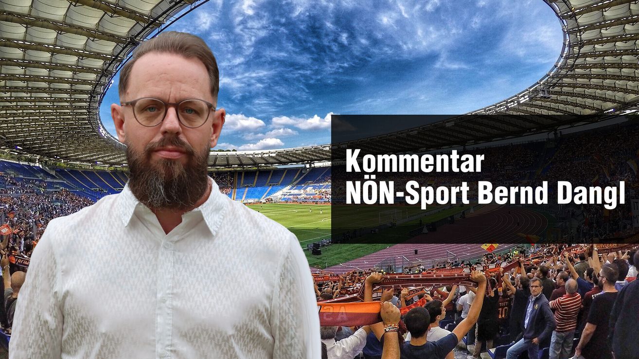 A man with glasses stands in front of a sports stadium, with a crowd below him holding a red and yellow banner.