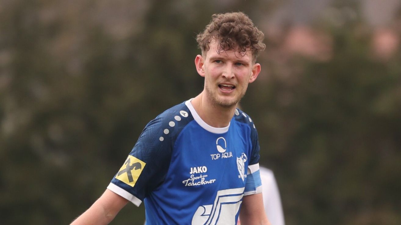 A man in a blue soccer jersey with the number 7, sponsored by Jako, runs on the field.