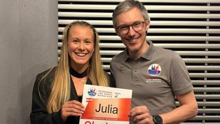 A man and a woman are smiling and posing for a photo, with the woman holding a certificate that reads Julia Oberbank Marathon.