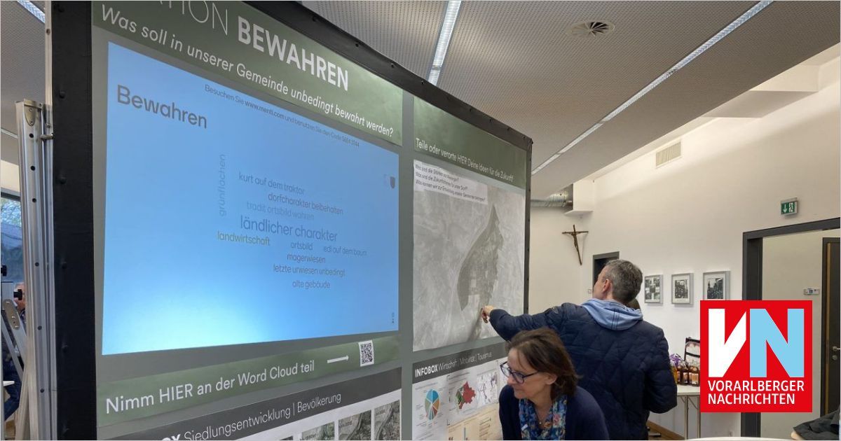 Zwei Personen betrachten einen großen Bildschirm, der historische Informationen und eine Karte anzeigt. Einer zeigt mit dem Finger auf die Karte, auf der ein QR-Code sichtbar ist.