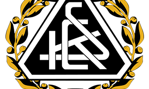 Ein dreieckiges Emblem mit dem Text 'HCS' in Weiß, umgeben von einem goldenen Lorbeerkranz mit gelben Blättern auf schwarzem Hintergrund.