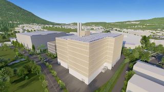 An aerial view of a modern building complex with solar panels on the roofs, situated in a green suburban area with hills in the background.