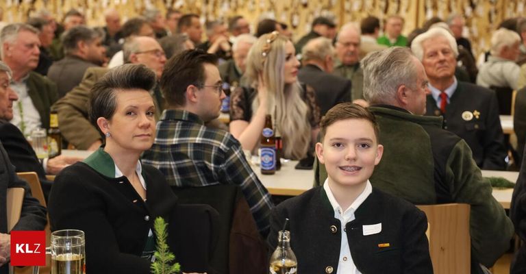 Eine Gruppe von Menschen, darunter eine Frau, ein Mann und ein junger Junge, sitzen in einem Restaurant. Der Junge hat ein Lächeln im Gesicht.