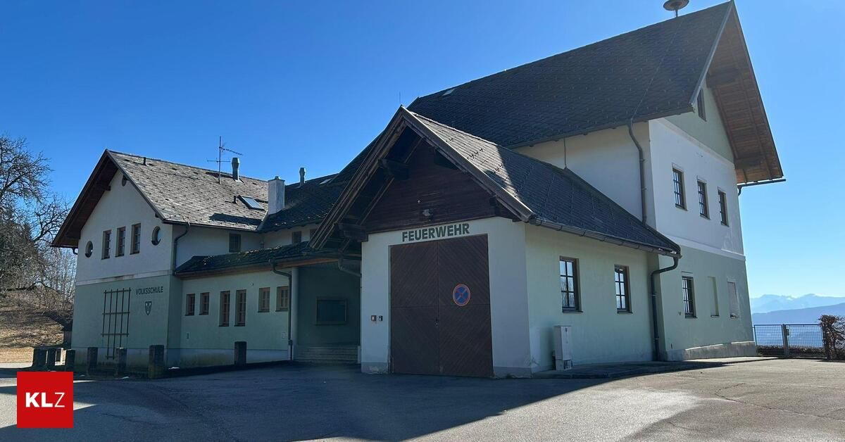 A fire station building with a brown door and a sign that reads Feuerwehr. The building has a chimney and several windows.