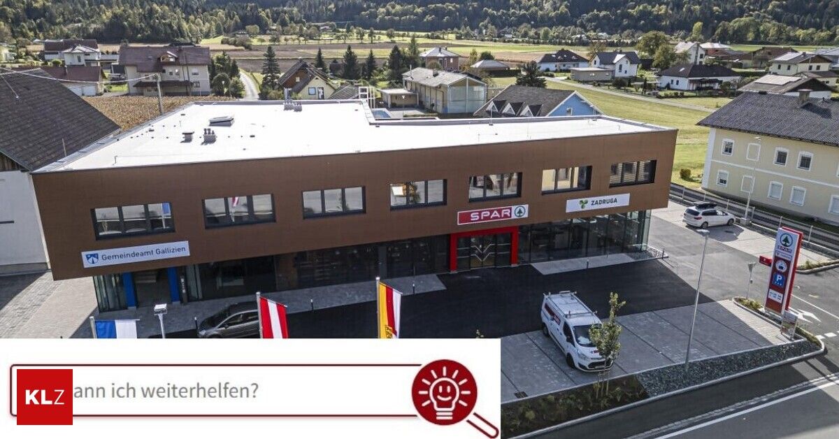 Ein Luftbild eines modernen Gebäudes mit Fahnen davor. Das Gebäude hat ein Schild mit den Aufschriften 'SPAR' und 'ZADUGA'. Vor dem Gebäude sind Autos geparkt. Ein weißer Lieferwagen ist auf der rechten Seite geparkt.