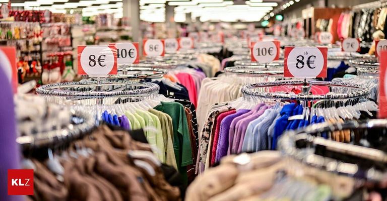 A clothing store with racks of clothes of various colors and sizes. Price tags are attached to the hangers, showing prices from 8 to 10 euros.