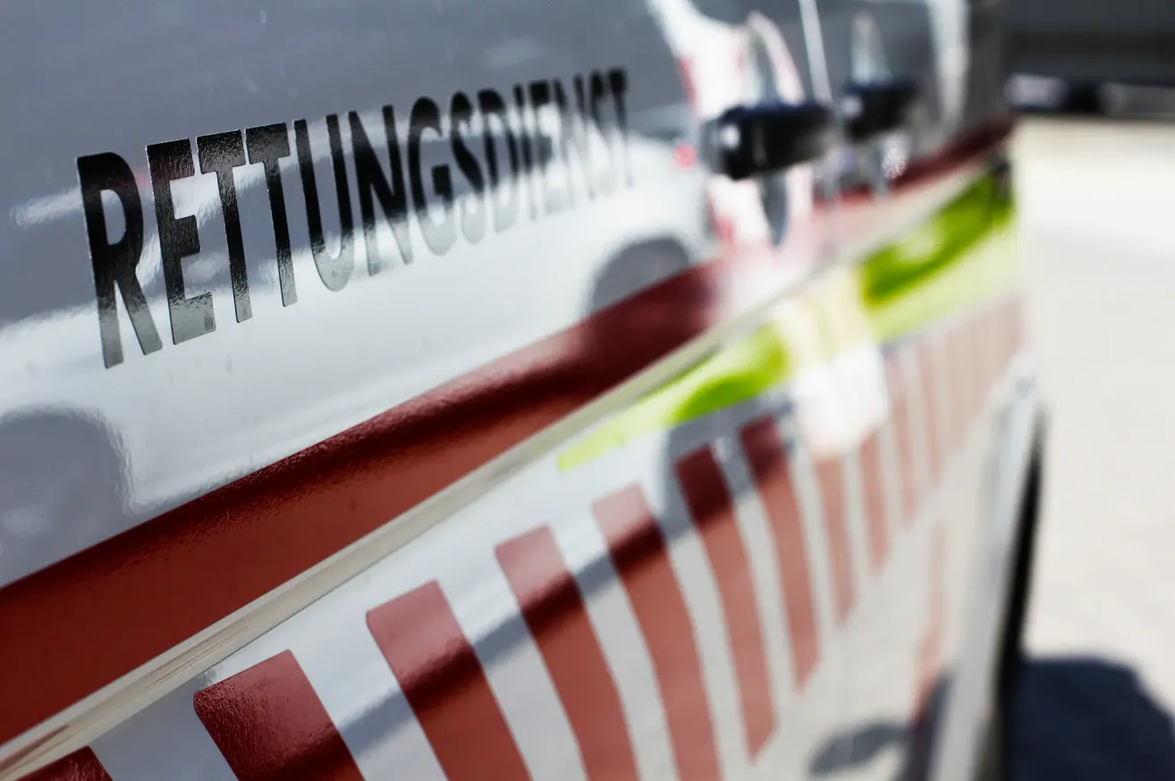 Nahaufnahme der Fahrzeugseite mit dem Wort 'TUNINGSERVICE' in fetten schwarzen Buchstaben. Das Bild ist unscharf und zeigt rote und weiße Streifen sowie eine Reflexion eines Lichts.