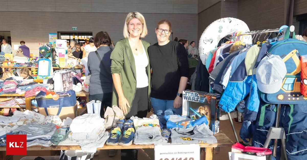 Zwei Frauen stehen hinter einem Tisch mit Kinderkleidung. Sie lächeln. Der Tisch hat eine Star Wars-Box, Schuhe und andere Kleidung. Andere Menschen sind im Hintergrund.