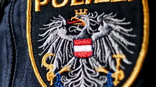 Nahaufnahme eines Polizeiabzeichens mit der Aufschrift 'POLIZEI' und einem Adleremblem in Rot, Weiß und Blau.