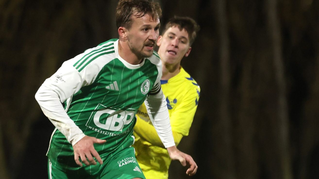 Zwei Fußballspieler in Aktion. Einer in Grün und Weiß, der andere in Gelb. Sie befinden sich mitten in einem Spiel.