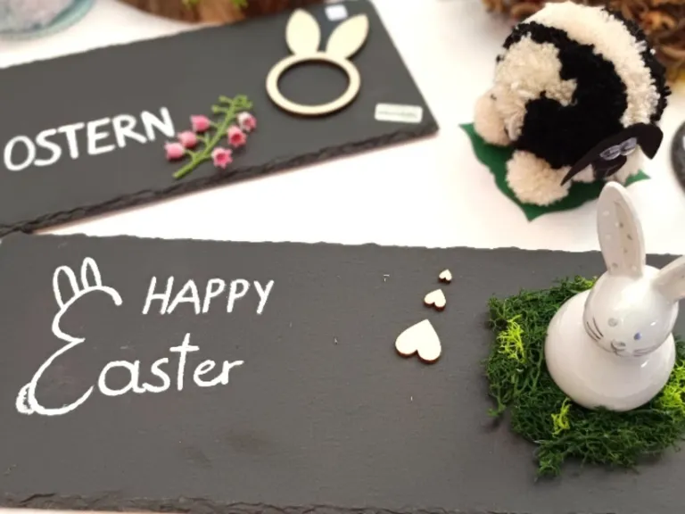 Ein Kreidetafel mit 'Frohes Ostern' darauf, einem Plüschtier und einem Schild mit 'ERN' und einem Hasenausschnitt.