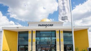 Ein weißes und gelbes Gebäude mit einer goldenen Kuppel auf der Spitze. Das Gebäude heißt Parndorf. Neben dem Gebäude befindet sich eine Fahne.