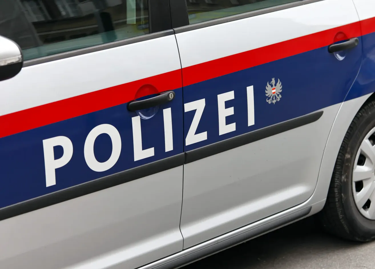 Eine Polizeiautotür mit dem Wort 'POLIZEI' darauf und einem Logo auf der Seite.