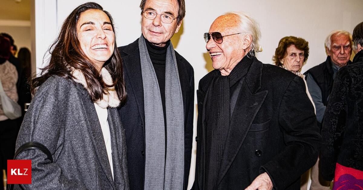 Drei Menschen stehen lächelnd zusammen. Eine Frau links und zwei ältere Männer neben ihr. Sie tragen Winterkleidung, und der Hintergrund ist weiß.