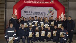 Eine Gruppe Feuerwehrleute posiert mit Zertifikaten in der Hand. Sie tragen Uniformen. Hinter ihnen befindet sich ein Banner mit der Aufschrift Nö Feuerwehr Funkleistungsabzeichen.