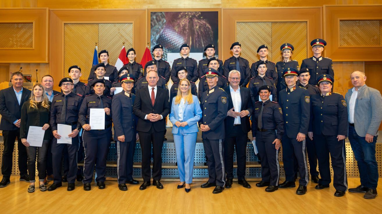 Eine Gruppe von Polizeibeamten, darunter zwei Frauen, steht für ein Foto zusammen. Ein Mann und eine Frau in Zivilkleidung sind ebenfalls auf dem Foto zu sehen. Sie alle lächeln.