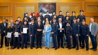 Eine Gruppe von Polizeibeamten, darunter zwei Frauen, steht für ein Foto zusammen. Ein Mann und eine Frau in Zivilkleidung sind ebenfalls auf dem Foto zu sehen. Sie alle lächeln.