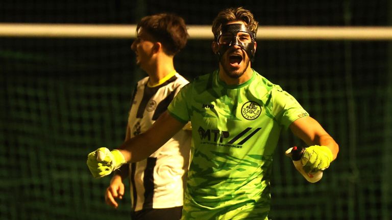 Ein Fußballspieler mit Maske feiert vor einem Tor, ein anderer Spieler steht hinter ihm.