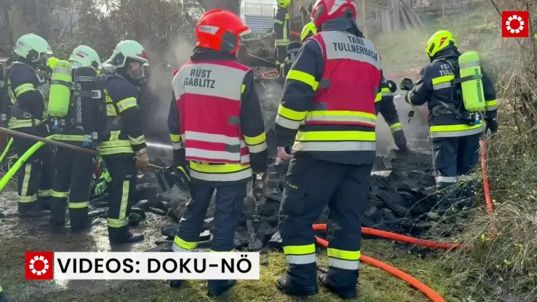 Feuerwehrleute in Schutzkleidung arbeiten an einem Brandort. Ein Feuerwehrmann heißt Rust, ein anderer Tank Tullerbach. Rauch und Trümmer umgeben sie.